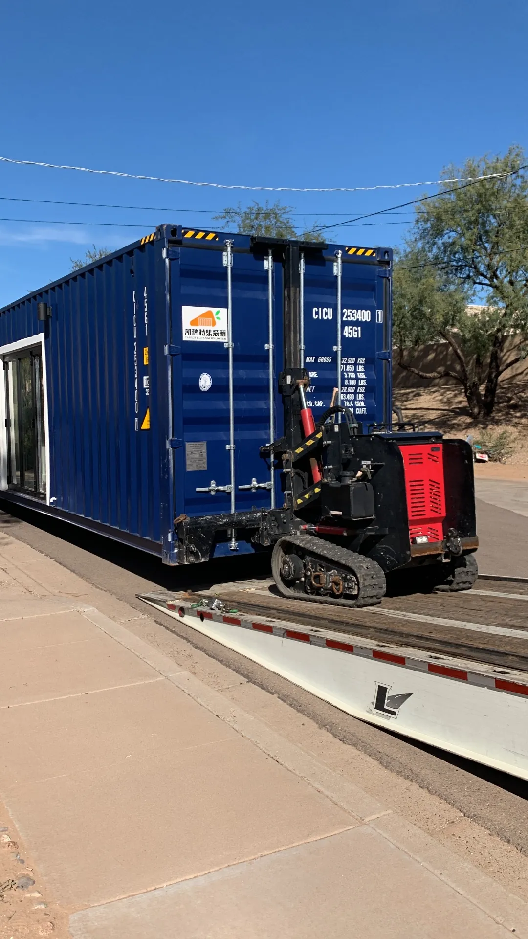 Remote-controlled track mover walking a container home off a trailer on an Arizona site
