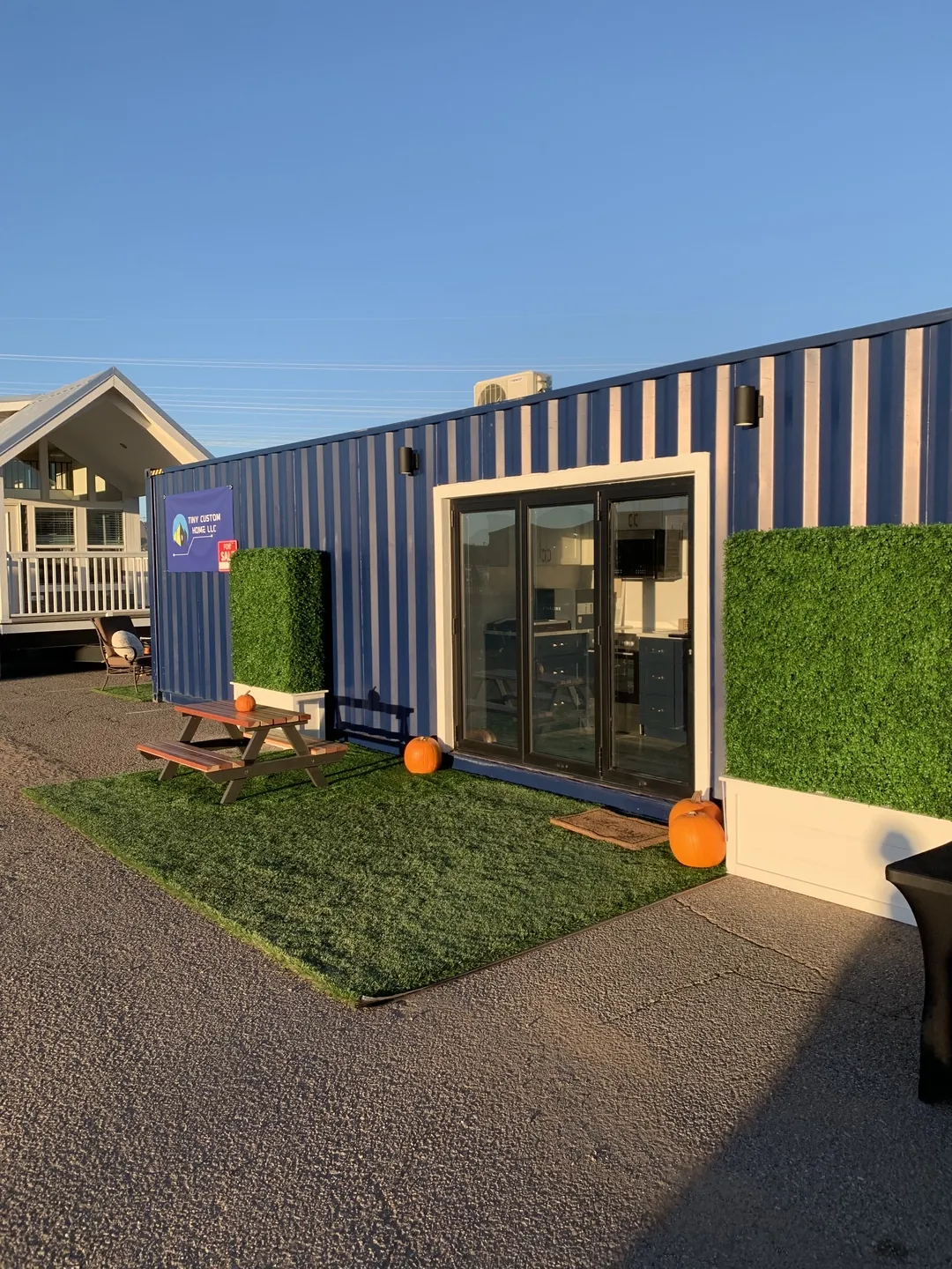 Finished Tiny Custom House container ADU in an Arizona backyard behind an existing house, with turf, pavers and a privacy screen