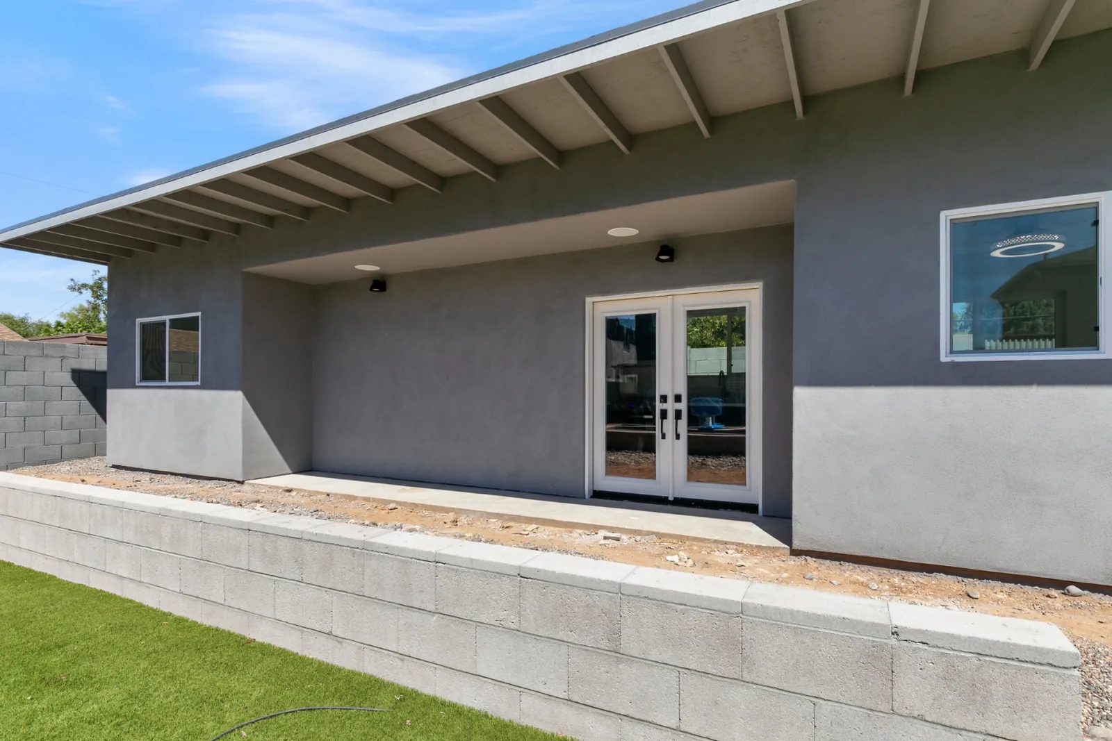 Completed detached stick-built casita in Arizona with grey stucco, a standing seam metal roof and french doors