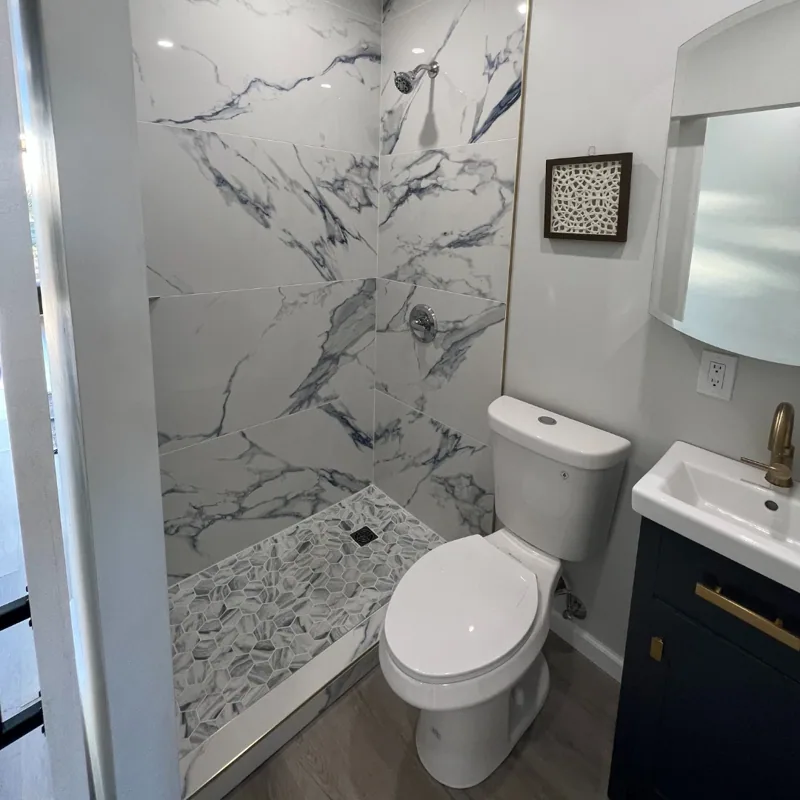 Full bathroom with a marble-look tiled shower inside a container home